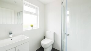 Une salle de bain moderne avec un lavabo blanc, des toilettes et une douche à parois de verre.