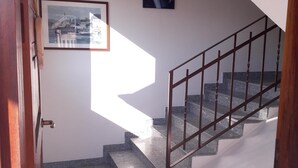 Una escalera con barandilla de metal, un cuadro enmarcado en la pared y una puerta a la izquierda.