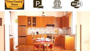 Cocina de apartamento de alquiler vacacional con armarios de madera, salpicadero de azulejos y una zona de comedor para cuatro personas.