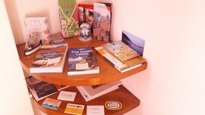 Una mesa de madera con libros y folletos de viajes, incluyendo títulos como "The Italian Lakes" y "Comalco at Sunset".