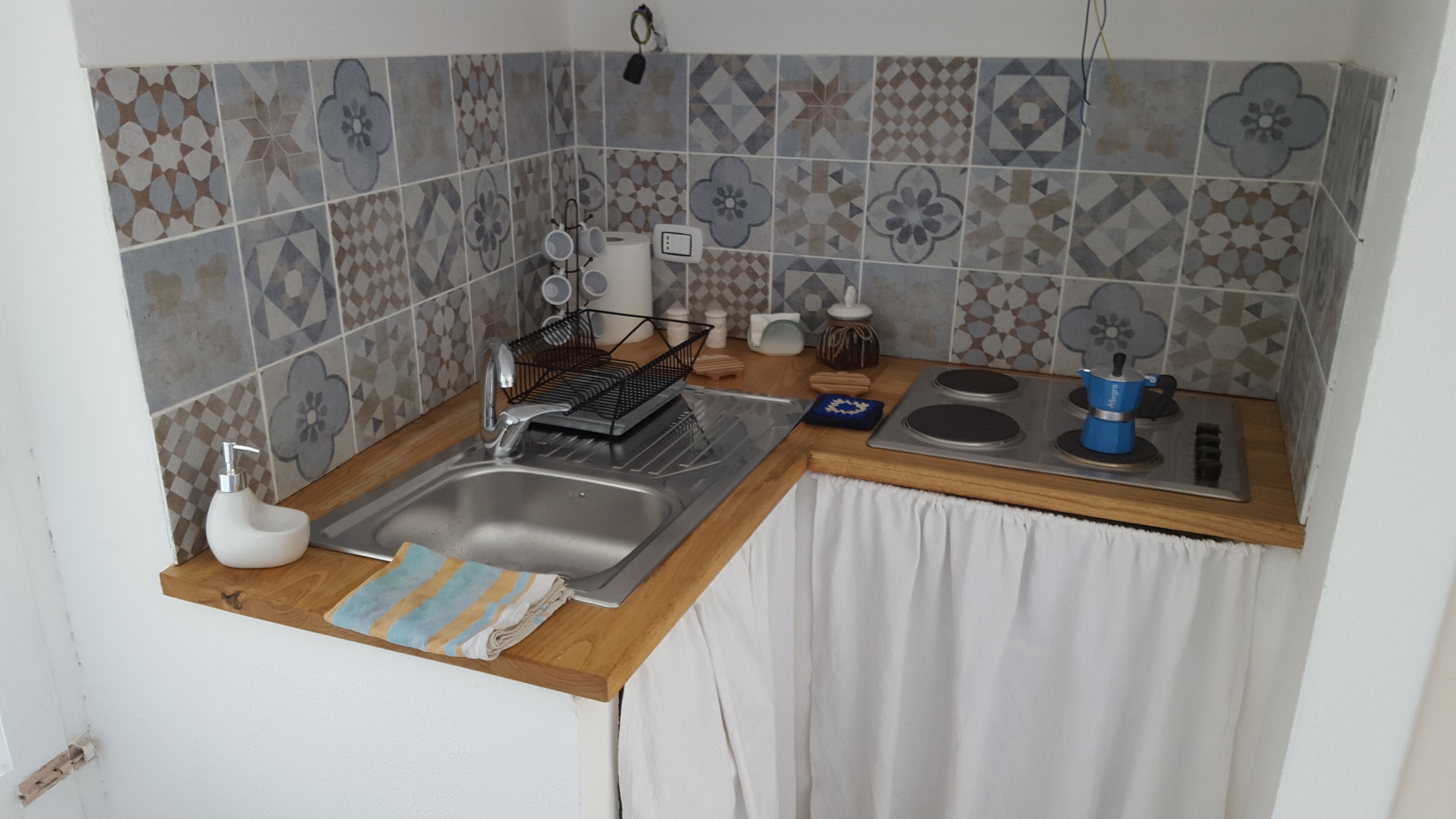 Una cocina pequeña con un lavabo, estufa y escurreplatos.