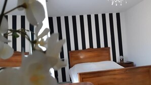 A bedroom with a wooden bed, a black and white striped wall, and a small bedside table with a lamp. - Casa Annunziata Badolato, Borgo, Mare and Olive Harvest (Badolato)