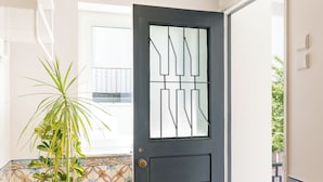 A door with geometric patterns, a potted plant, a tiled floor, and a window with a balcony view. - Apartment 4 bedrooms (2) - Porto (Porto)