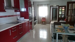 A modern kitchen with red cabinets, stainless steel appliances, and a dining area with a table and chairs. - Casa El Tonelero with garden and private pool (Gáldar)