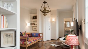 Une chambre confortable avec un lit en bois, un bureau avec un ordinateur portable, une lampe rouge et un téléviseur.