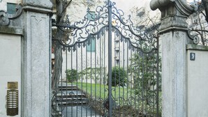 Un portail en fer forgé, avec un pilier en pierre et une plaque portant un numéro.