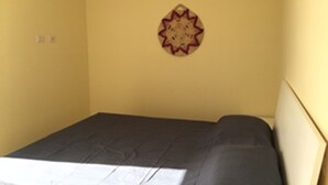 Una cama individual en una habitación con una pared amarilla lisa y un adorno de pared decorativo.