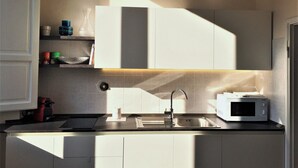 Una cocina moderna con microondas integrado, pileta de acero inoxidable y una lámpara colgante.