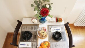 Una mesa de comedor adornada con un florero, un cuenco de naranjas y un recipiente de vidrio con aperitivos.