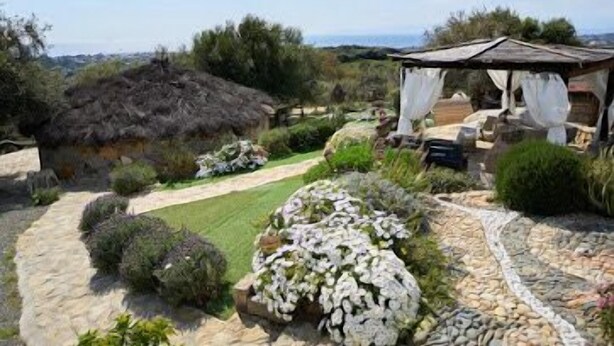 A garden with a thatched-roof structure, a stone pathway, and various plants. - Sardinian style holiday home (Quartu Sant'Elena)