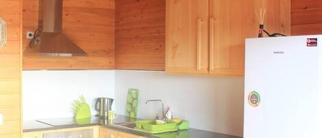 Cocina compacta con armarios de madera, horno de acero inoxidable, lavadora y refrigerador blanco.