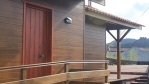 Un bâtiment en bois avec une porte rouge et un banc en bois à l’extérieur.