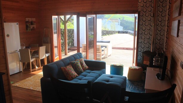 L’intérieur chaleureux d’un chalet comprend un canapé, des fauteuils, une petite table et un coin cuisine.