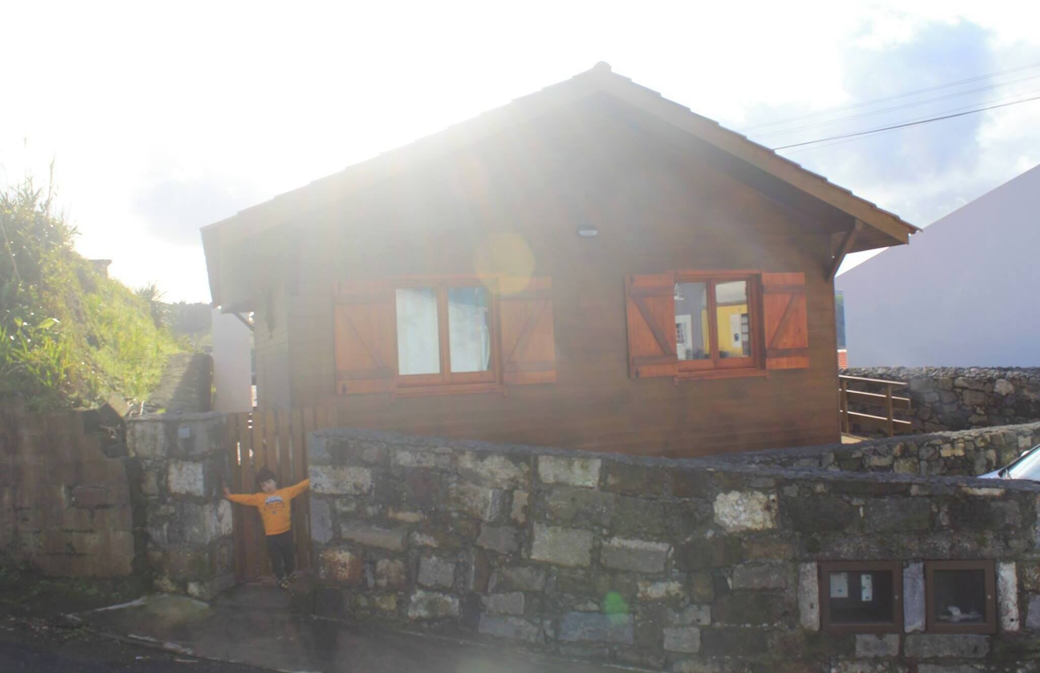 Un rústico edificio de piedra con techo de madera y dos ventanas con contraventanas.