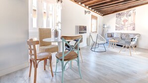 A modern living room with a wooden ceiling, a round dining table, and various seating options including wicker chairs and a sofa. - ~SILVER~ by myhomeintoledo.com (Toledo)