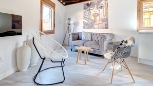 A cozy living room with a grey sofa, two patterned chairs, a small wooden table, and a large abstract painting on the wall. - ~SILVER~ by myhomeintoledo.com (Toledo)