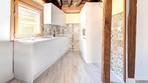 A narrow kitchen with white cabinets, a wooden floor, and patterned tile backsplash. - ~SILVER~ by myhomeintoledo.com (Toledo)