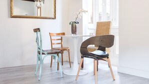 A dining area with a white table, two chairs, a vase with flowers, and a mirror on the wall. - ~SILVER~ by myhomeintoledo.com (Toledo)