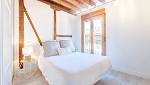 A bedroom with a bed, a small bedside table with a lamp, and a view of the outside through a glass door. - ~SILVER~ by myhomeintoledo.com (Toledo)