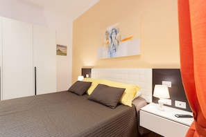 A hotel room with a bed, nightstand, and artwork on the wall.