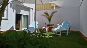 A small patio with two lounge chairs, a small table, and a potted plant.