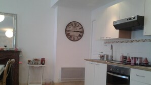 A kitchen with white cabinets, a stove, and a clock on the wall.