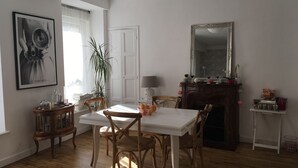 A dining area with a white table and chairs, a mirror, a fireplace, and a potted plant.