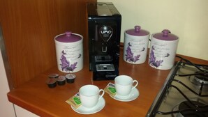 A coffee station with a coffee maker, two cups, and two containers on a wooden counter. - Katane Holidays "Verdi Apartment with Triple Room" (Catania)