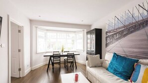 Una sala moderna con comedor, un ventanal y vista panorámica de la ciudad.