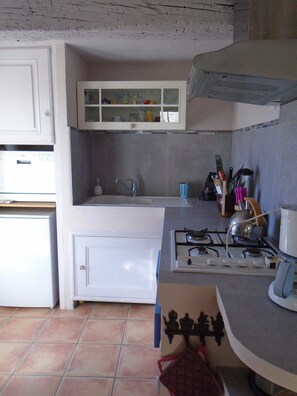 Functional kitchen with gas stove, sink, and refrigerator.