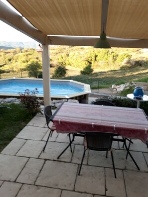 Relax in a serene outdoor setting with a covered patio featuring a hot tub and comfortable seating.