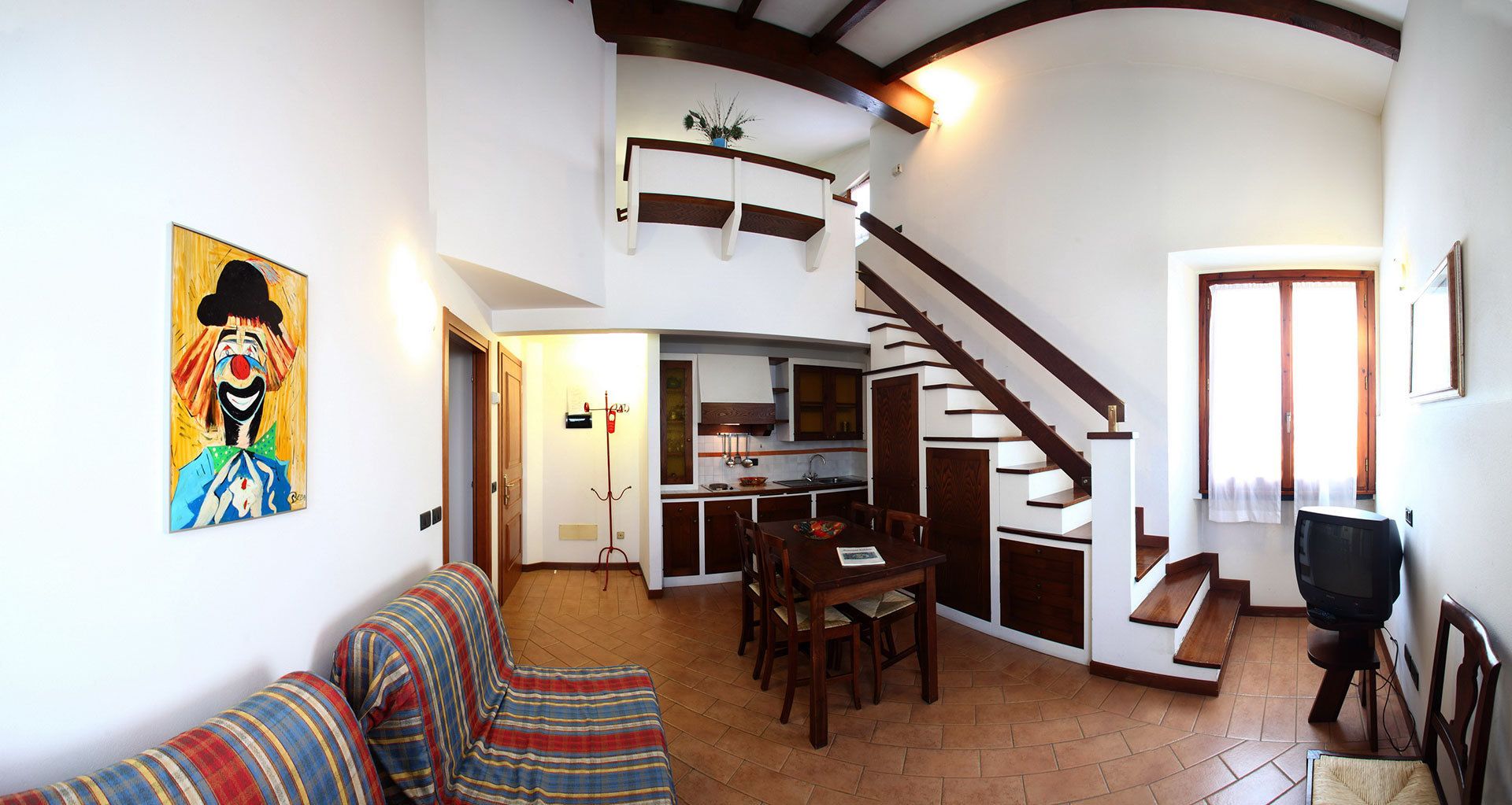 A spacious living area with a sofa, a dining table, and a kitchen in the background.