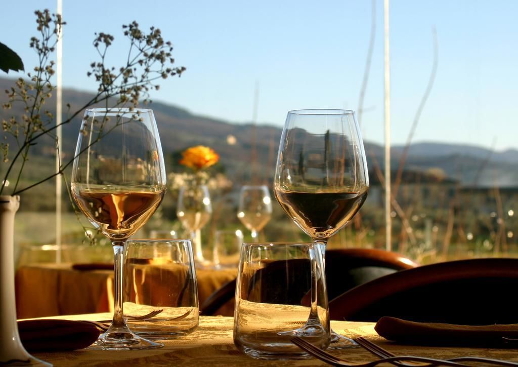 A table with three wine glasses, a vase with flowers, and a view of the countryside.