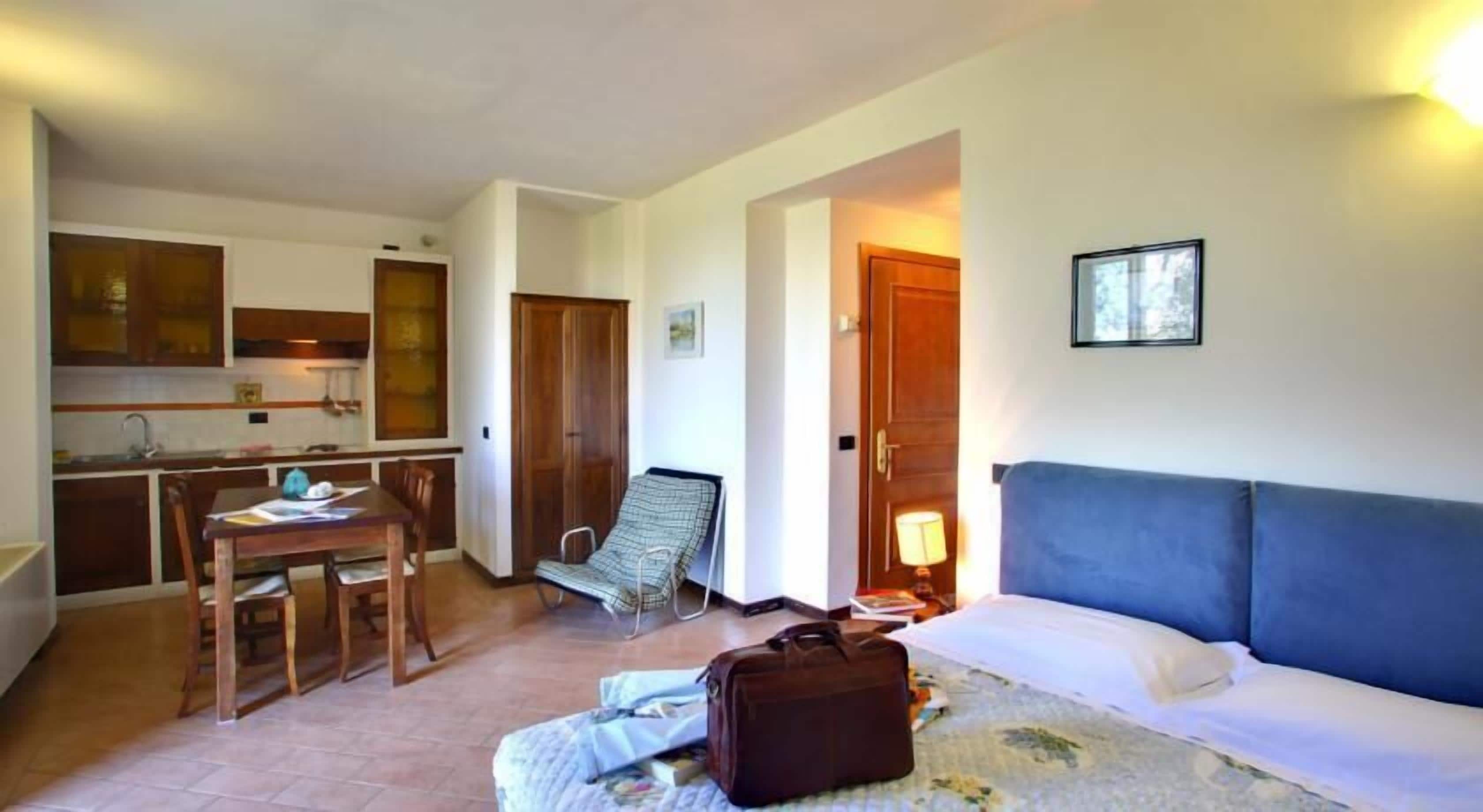 Een compacte leefruimte met een kitchenette, een eethoek, een fauteuil en een slaapbank.