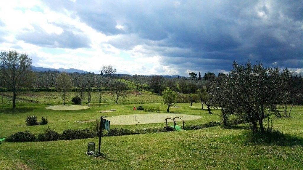 A golf course with multiple greens and a flagstick.