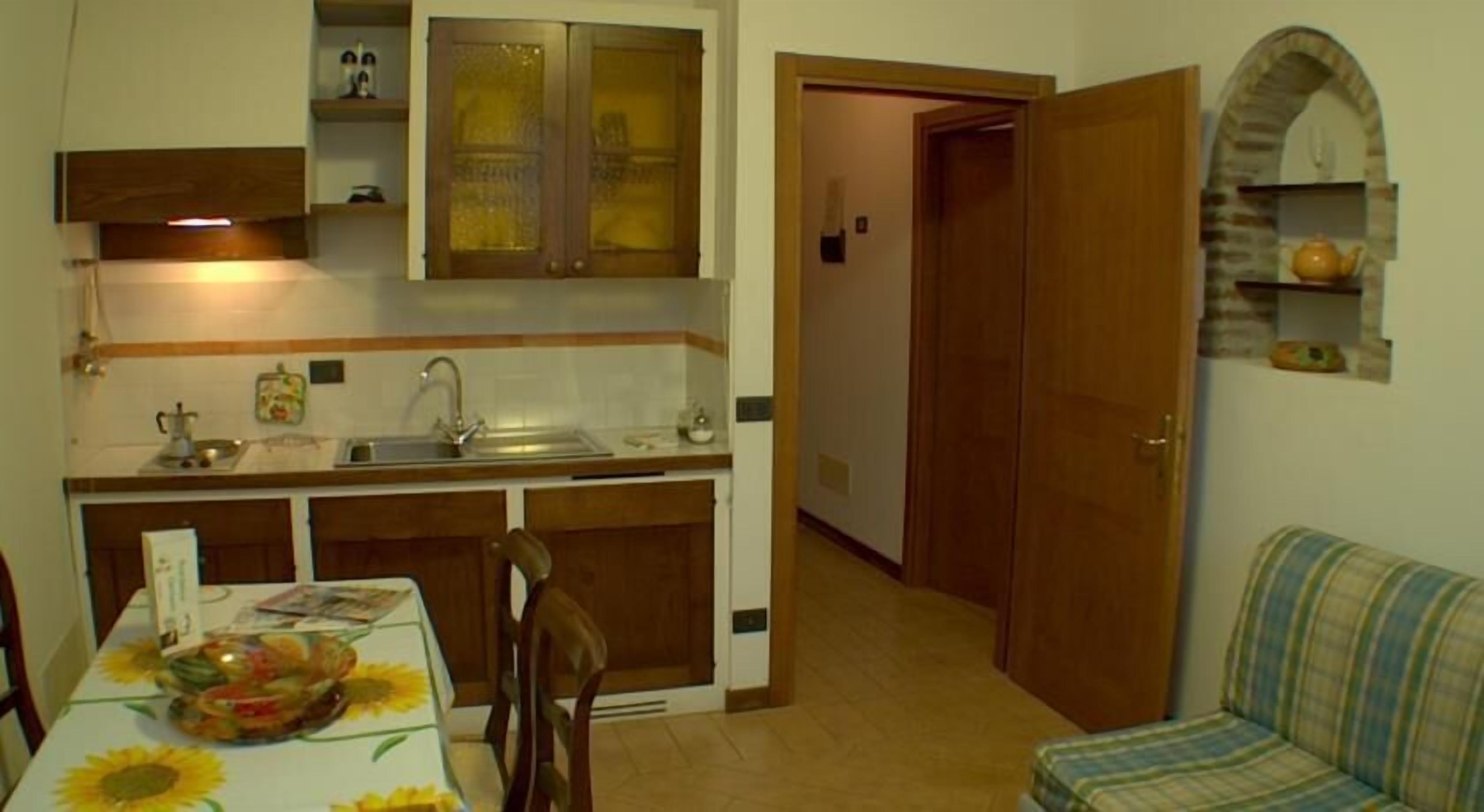 Cocina compacta con lavamanos, armarios y una mesa de comedor con mantel floreado.