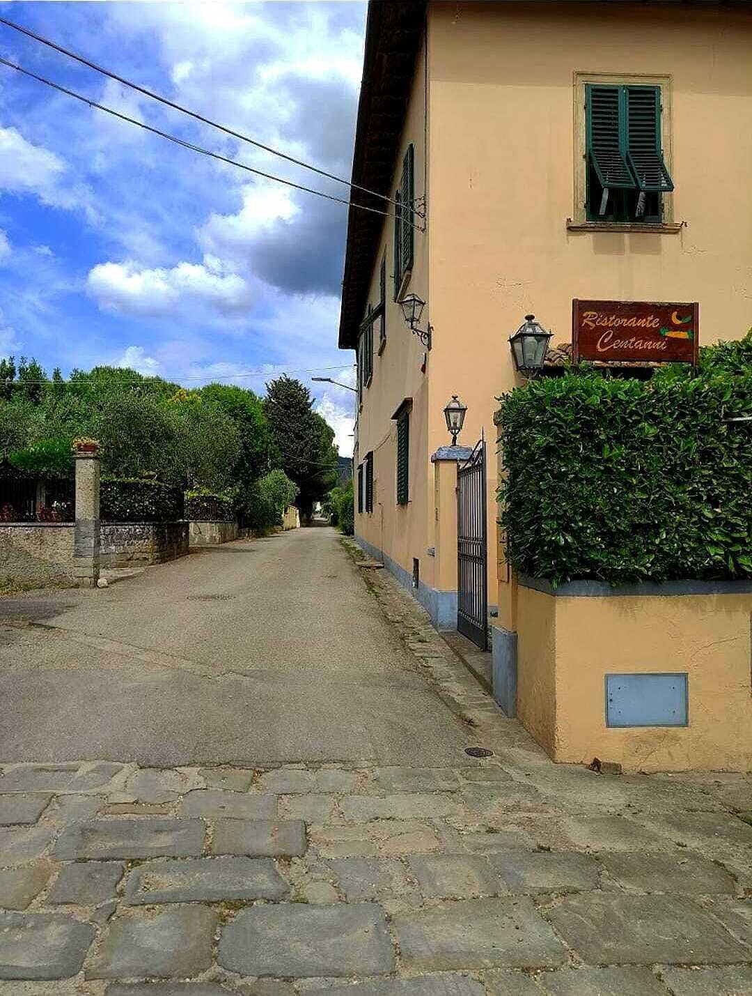 A narrow cobblestone street flanked by buildings with a restaurant sign.