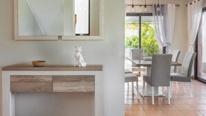 A modern dining area with a wooden table and grey chairs, a white statue on the counter, and a large mirror above. - New Casa Bondi by Your Madeira Rentals (Ponta do Sol, Madeira Island)