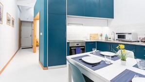 Eine moderne Küche mit blauen Schränken, einer weißen Arbeitsplatte und einem Essbereich mit Tisch für zwei Personen.