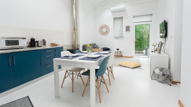 Eine moderne Küche mit blauen Schränken, einem weißen Esstisch und einem großen Fenster.