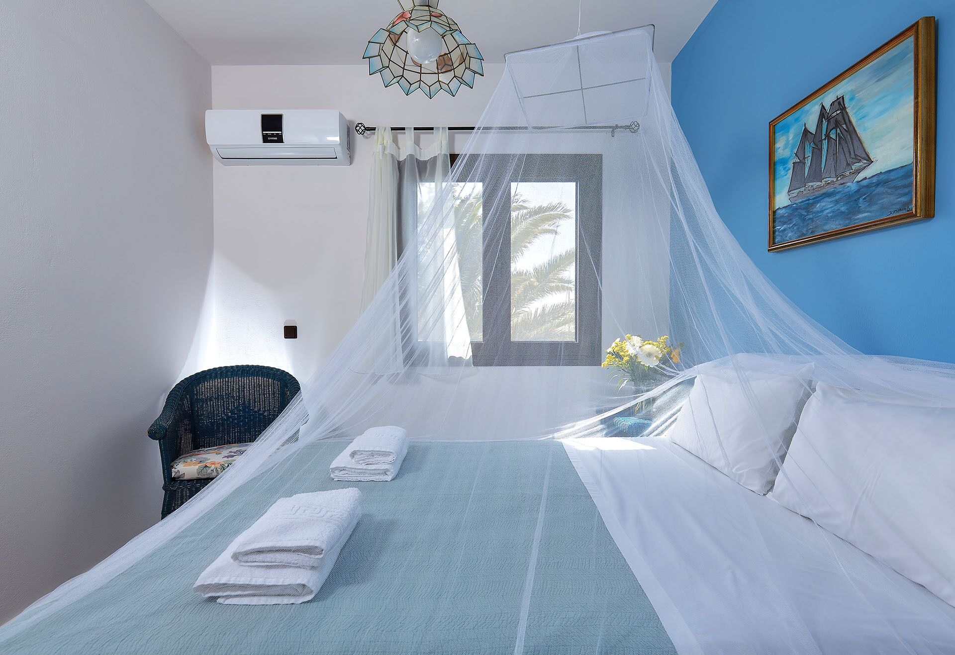 Un dormitorio con cama, ventana con vistas, un cuadro en la pared y equipo de aire acondicionado.