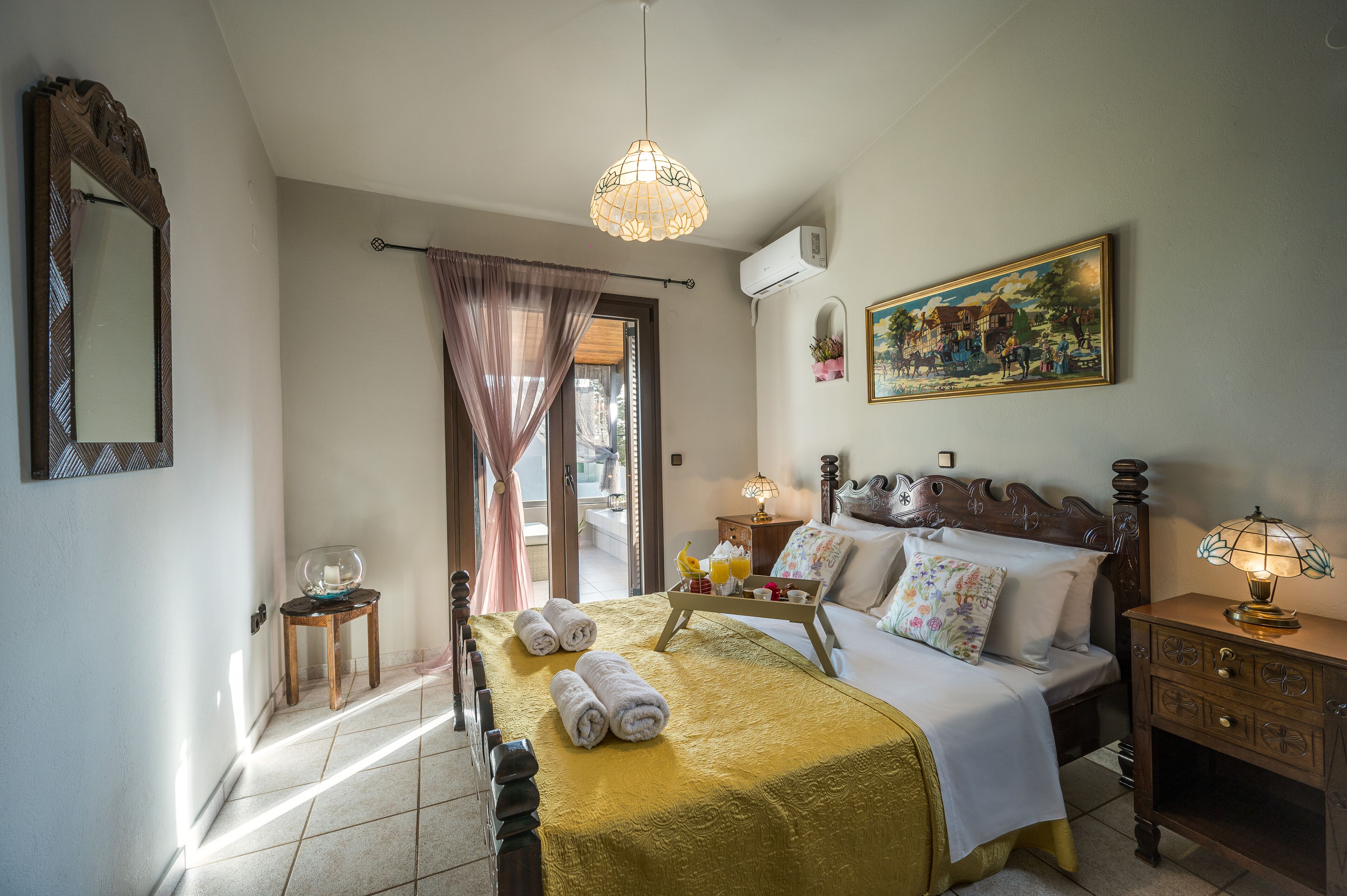 A hotel room with a bed, bedside table, lamp, and a painting on the wall.