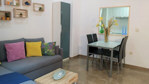 Una sala de estar moderna con un sofá gris, una mesa de centro y un comedor con mesa y sillas.