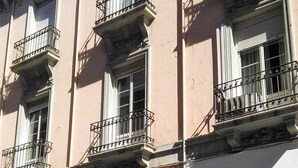 Un edificio con varios balcones, una puerta de madera y un letrero que dice 'Kolosem Pelequerias & Agora'.