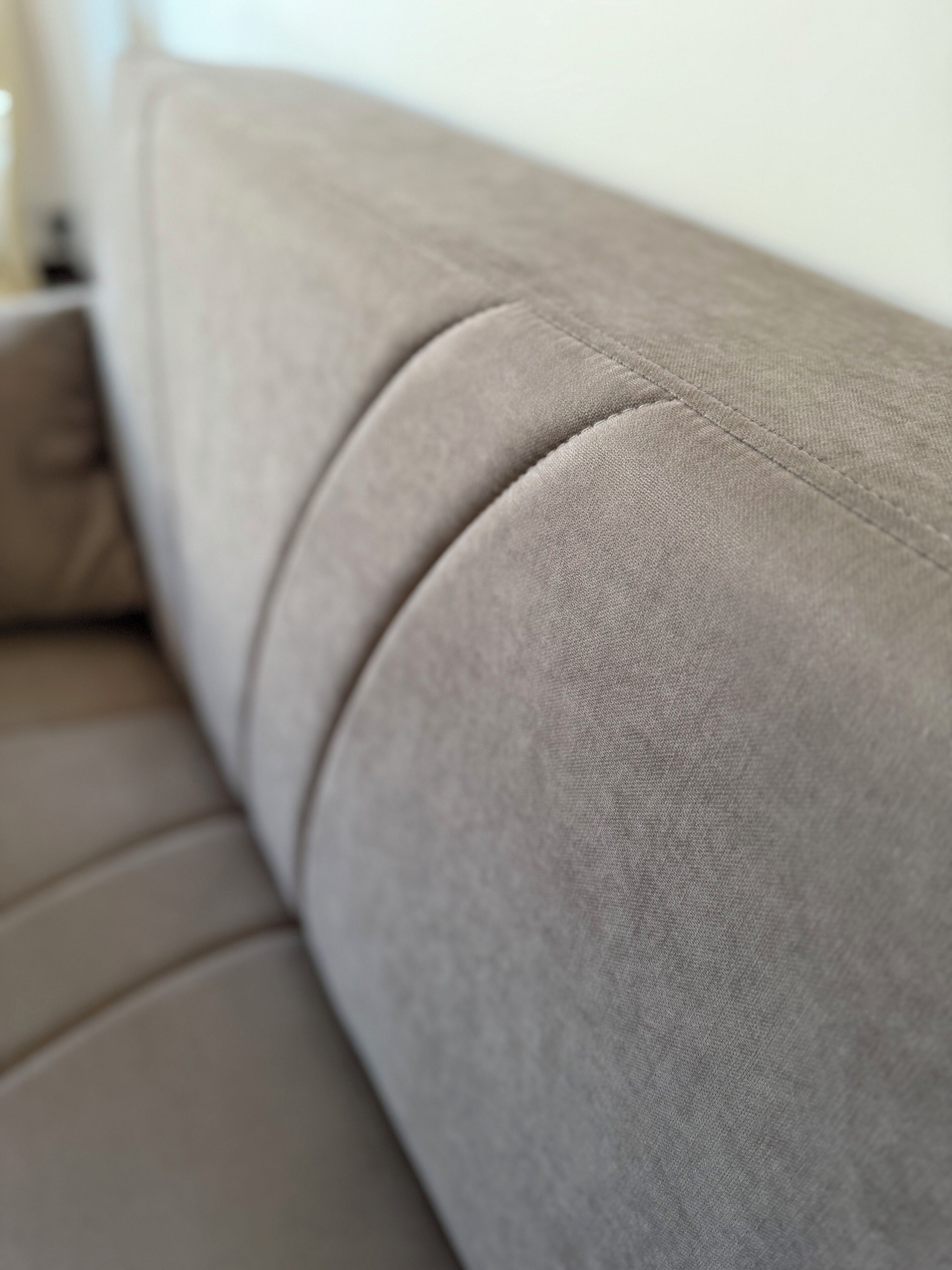 Ein Detailaufnahme eines Sofas mit glatter, gepolsterter Oberfläche und einer sichtbaren Naht.