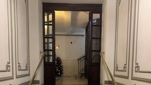 Een trap met een kamerbreed tapijt aan de voet, leidend naar een ruimte met een kerstboom.