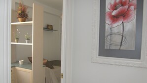 Une chambre à coucher comprenant un lit, une table de chevet, une commode et une étagère avec des plantes et une horloge.