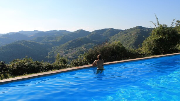 Eine Person in einem Schwimmbecken, im Hintergrund eine gebirgige Landschaft.