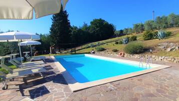 Enjoy a refreshing swim in the pool surrounded by lush greenery and shaded areas.