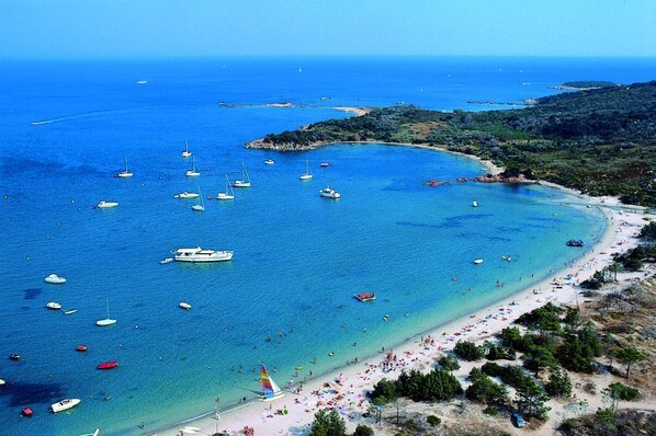 Une zone côtière avec des bateaux, une plage et un paysage vallonné.